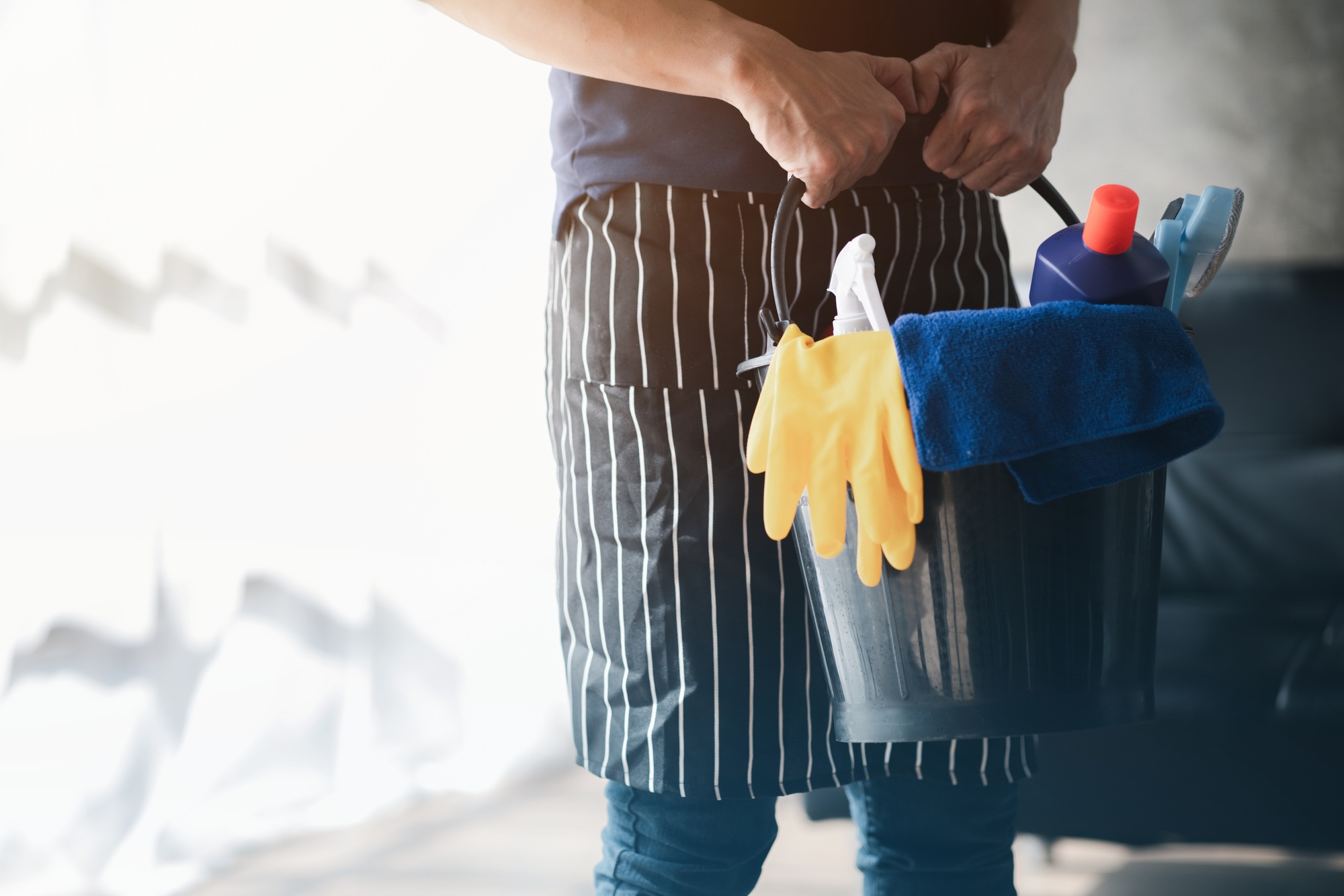 Person cleaning the room, cleaning staff standing holding a bucket of cleaning equipment.